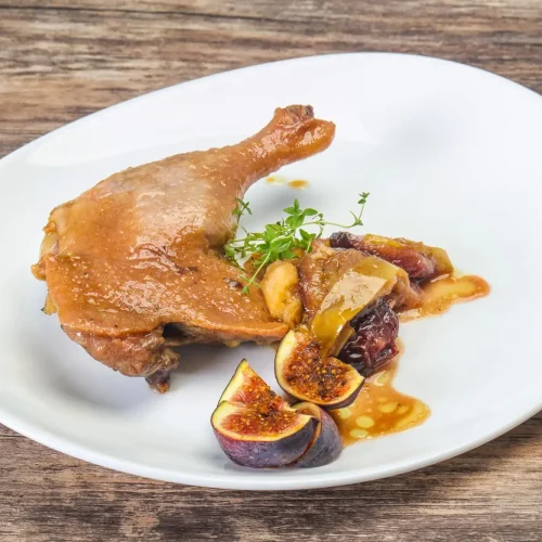 Assiette de cuisse de canard servi avec quelques tranches de figues