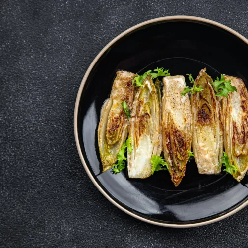Endives parfaitement braisées servies dans une assiette noire