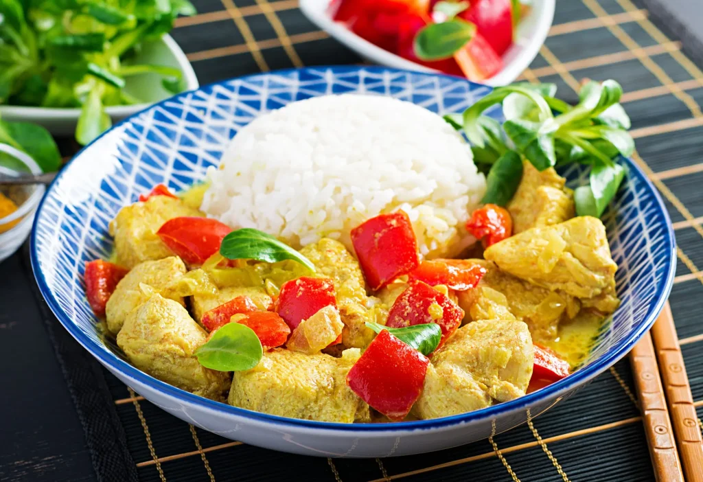 Assiette d'aiguillettes de poulet au curry servi avec du riz