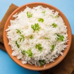 Riz basmati cuit servi dans un bon avec quelques feuilles de coriandre