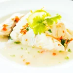 Dos de cabillaud servi avec sa sauce dans une assiette