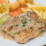 Escalope de veau servie avec des frites et quelques légumes
