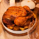 Poulet entier rôti servi avec des pommes de terre