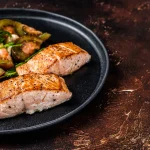 Rôti de saumon servi dans une assiette avec une petite salade de tomates