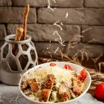 Assiette de salade de pâtes poulet et cacahuètes parsemée de fromage