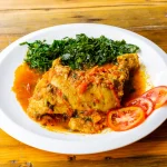 Assiette de moambe servi avec des épinards