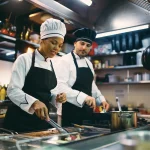Personnel préparant des repas dans une cuisine professionnelle équipée de matériel en inox